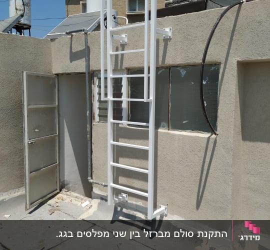 סולם מתכת לבן מותקן על קיר בטון